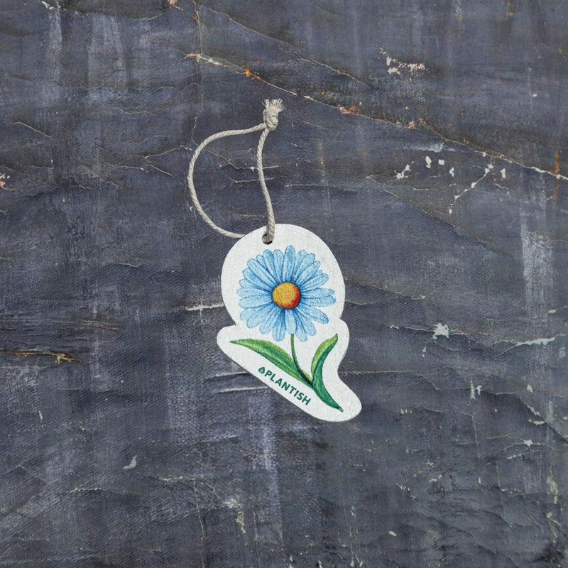 Top view of an eco-friendly cellulose pop-up kitchen sponge featuring a delightful blue daisy pattern, complete with hanging cord. This innovative cleaning tool lies completely flat when dry (just 0.3cm thin) for space-saving storage, then expands to a full 1.5cm thickness when wet for superior absorbency. Made from 100% biodegradable plant-based cellulose, the sponge combines sustainable functionality with charming floral aesthetics - the vibrant blue daisy design adding a cheerful touch to kitchen chores 