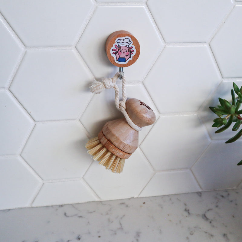 The wooden dish brush hangs on white tile walls.