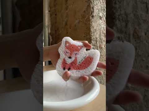Video of hand soaking an eco friendly fox pop up sponge and expanding in water.